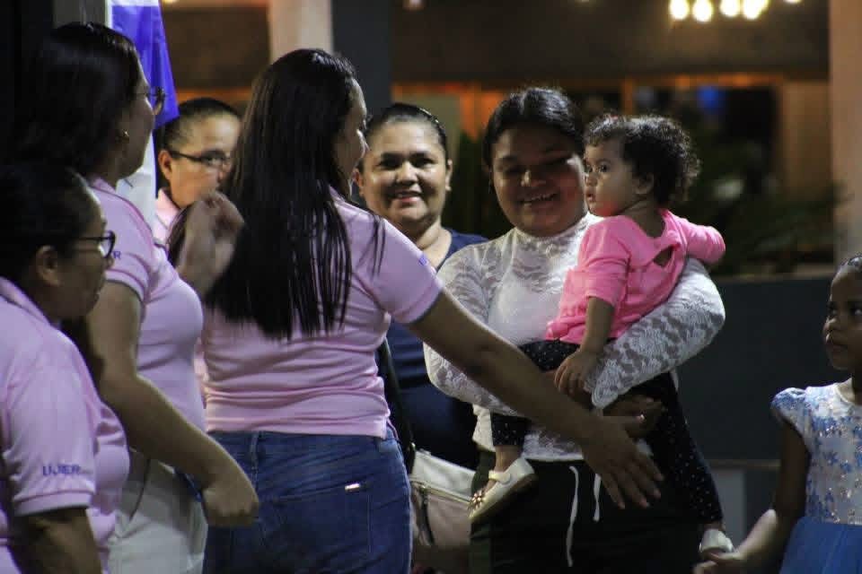 Equipo de mujeres recibiendo y sirviendo a una familia en Oasis de Amor